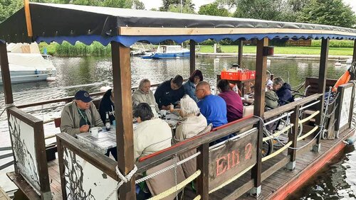 Eine Gruppe älterer Herrschaften fährt in einem großen Floß auf dem Wasser
