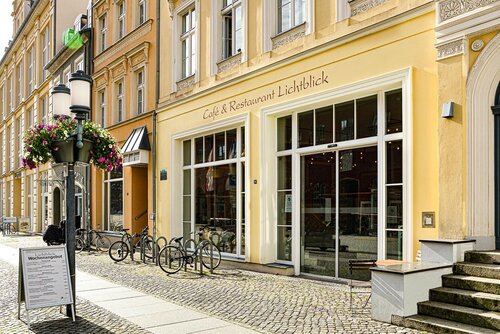 Außenansicht des Café und Restaurant Lichtblick vom Greifswalder Rathaus aus mit Aufsteller Mittagstisch und Blumenschmuck