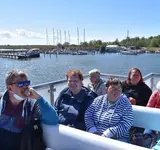 Eine Gruppe Menschen sitzt auf einem Schiff, das auf dem Wasser fährt.