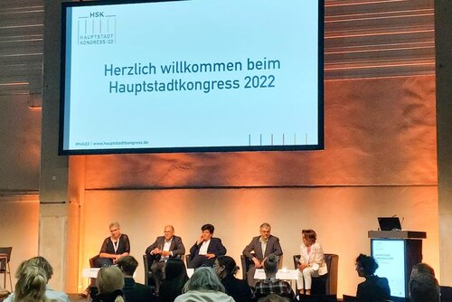 Fünf Menschen sitzen auf einer Bühne vor Zuschauern