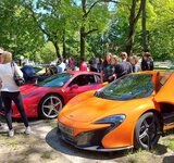 Mehrere Sportwagen stehen nebeneinander. Menschen schauen sie sich an.