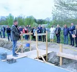 Viele Personen stehen auf einr Baustelle, eine Person hält eine Rede
