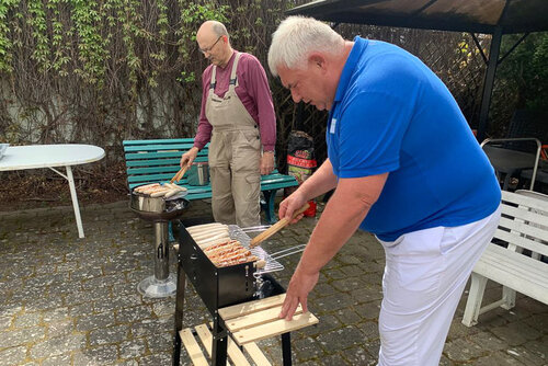 Zwei Männer grillen Bratwürste auf einem Grill