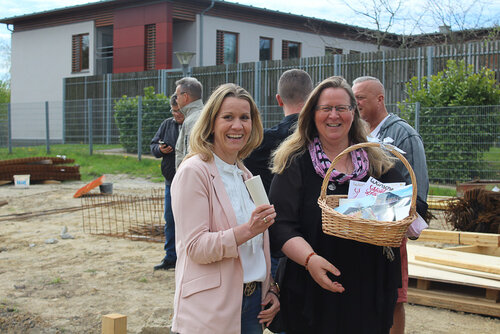 Zwei Frauen haben einen Präsentkorb und blicken in die Kamera